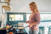 Woman making pancakes fro breakfast in the kitchen at home