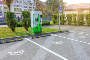 Electric car charging filling station parking next to city park. Future transport technology.