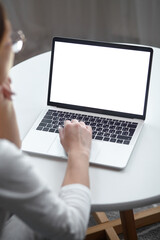 Mockup white screen laptop woman using computer while sitting at table at home, back view