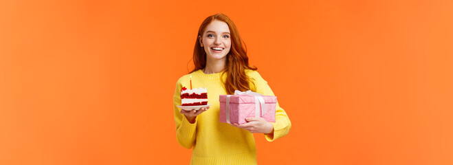 Wall Mural - Holidays, celebration and people concept. Cheerful gorgeous redhead girlfriend receive cute gift, holding present in wrapped box and piece cake with candle, smiling celebrate birthday, b-day party