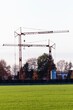 Vertical view of cranes working in the countryside before a white skyline