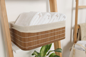 Wall Mural - Soft towels in wicker basket on decorative ladder near white wall