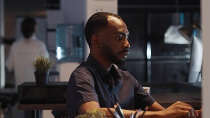 Confident employee using laptop to plan startup report in company office, working late at night to create professional presentation. Writing executive email with e commerce data and business shares.