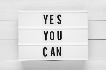 Wall Mural - Lightbox with phrase Yes You Can on white wooden table, top view. Motivational quote