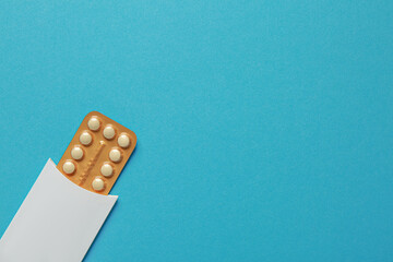 Birth control pills on light blue background, top view. Space for text