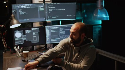 IT system engineer comparing data files on clipboard papers and multiple monitors to program new server interface. Developing html script on terminal window, coding database. Handheld shot.