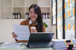 © itchaznong - Asian Business woman working at home office and analyze financial report document. Accounting and Finance concept