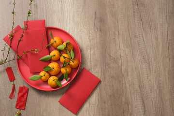 Wall Mural -  Asia traditional holiday. Lucky money, lucky ornaments, mandarin oranges, and branch flower on a wooden table.  Space for text. Chinese lunar new year background.