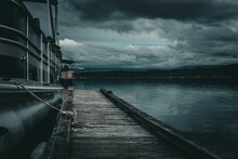 View Of A Ship Docked From A Wooden Pier Under The Dark Cloudy Sky