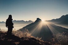  A Person Standing On A Hill With A Backpack In The Foreground And The Sun Shining Through The Mountains.