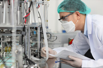 Poster - Worker in personal protective equipment or PPE inspecting quality of mask and medical face mask production line in factory, manufacturing industry and fac