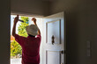 Man applying draught stopping foam tape to the door frame. Home maintenance to meet the healthy home standard. Auckland.