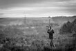 Grayscale shot of a hunter shooting in the air