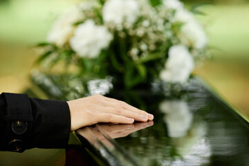 Wall Mural - Close up of female hand on coffin saying goodbye at outdoor funeral ceremony, copy space