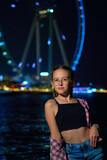 girl on the background of a Ferris wheel at night on the seashore