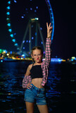 girl on the background of a Ferris wheel at night on the seashore