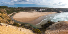 Panoramic view of Praia de Odeceixe Mar Surfer beach with golden sand, atlantic ocean waves, river bend and white houses of Odeceixe village. Rota Vicentina coast, Odemira, Portugal.