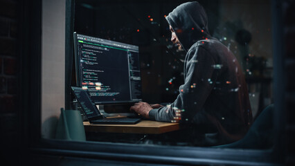 Fototapete - Hacker Using Desktop Computer to Perpetuate Cyber Attack, Doing DDOS Attack, Sends Viruses, Phishing Software, Malware, Stealing Private Data, Credit Card Fraud. Shot into City Apartment Window.
