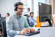 © Bojan - Young male technical support dispatcher in call center. Man in call center with headset helping customer.