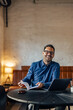 © bnenin - Smiling male being at the office, opening his notebook, using a laptop.