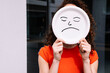 © VISTA by Westend61 - Young woman holding sad emoticon plate over face