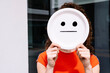 © VISTA by Westend61 - Young woman holding straight smiley emoticon plate over face