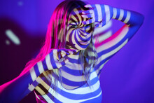 Young woman with illuminated swirl pattern in front of wall