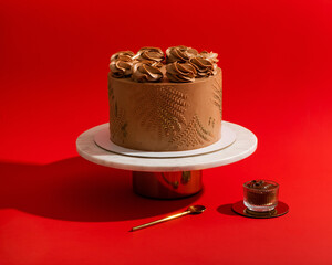 Sticker - Beautiful party chocolate cake with cream on white stand, on red background with chocolate sauce closeup horizontal view.