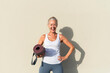© VISTA by Westend61 - Happy woman with hand on hip in front of cream colored wall on sunny day