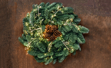 Wall Mural - christmas wreath with golden lights on dark rustic background top view, copyspace. xmas garland, new