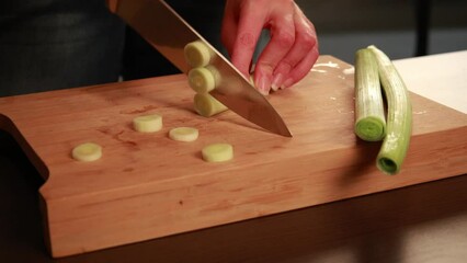 Canvas Print - woman hands cutting leek on wooden board close up