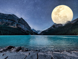 Wall Mural - Big moon glowing over rocky mountains and starry on Lake Louise in the night at Banff national park