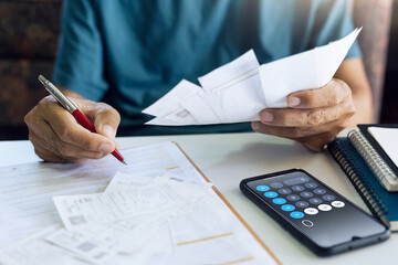 Wall Mural - Stressed asian man using smartphone calculating receipt payment, monthly expenses, taxes, bank account balance and , Income is not enough, no money in pocket for expenses