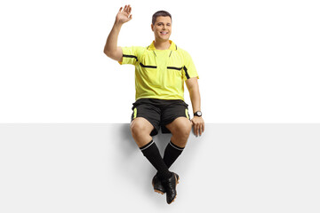 Wall Mural - Full length portrait of a football referee sitting on a blank panel and waving