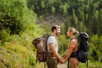 Wall Mural - White couple holding hands while hiking in green forest