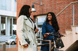 © Drobot Dean - Two young joyful women walking with bicycle through city street