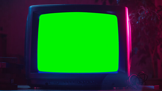 Fototapete - Close Up Footage of a Dated TV Set with Green Screen Mock Up Chroma Key Template Display. Nostalgic Retro Nineties Technology Concept. Vintage Television Display in Neon Lit Living Room.