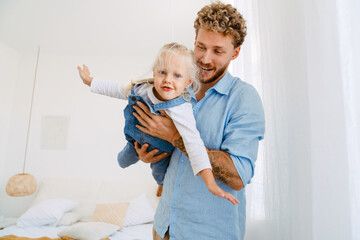 Young father holding his little daughter in hands while playing at home