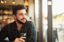 Bearded Man In Bar Near To Window Drinking Beer