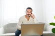 © Louis-Paul Photo - man with black hair using laptop at home sofa and talking to his cellphone