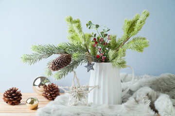 Wall Mural - Christmas table decoration with pine tree branches in vase and ornaments over bright background