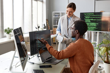 Software developers discussing programming code when working on new application for VR headset