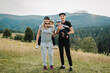 © Serhii - Mother, father hug childs in autumn. Family with kids hiking on grass on top of a mountains. Tourists enjoy valley view sunset. Mom, dad, son, and daughter. Holiday trip concept. World Tourism Day.