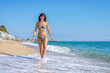 © Cavan Images - Front view of beautiful smiling woman in swinsuit walking on beach