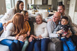 © Cavan Images - Portrait of multigenerational family sitting on living room couch