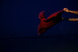 © Cavan Images - A woman in a bikini waves a red towel on the beach near the ocean at dusk.
