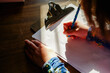 © Cavan Images - close-up of a small child sitting in a patch of light doing homework