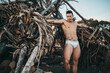 © Cavan Images - muscular man in briefs leaning against dry house-shaped trees
