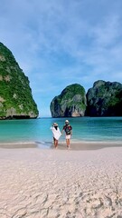 Wall Mural - Couple of white men and Asian women walking on the beach of May Bay Koh Phi Phi Thailand in the morning