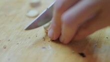 Close Up Footage Of Woman Cutting Fresh Ginger Root On Wooden Cutting Board. One Of Ingredients For Tom Yam, Asian Spicy Soup. Cooking Traditional Food In Kitchen At Home.